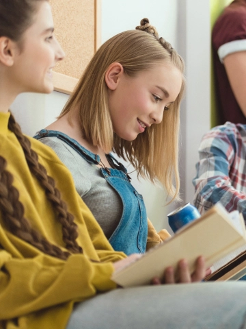 Dve mladé dievčatá si spolu čítajú v ich triede počas prestávky v škole.
